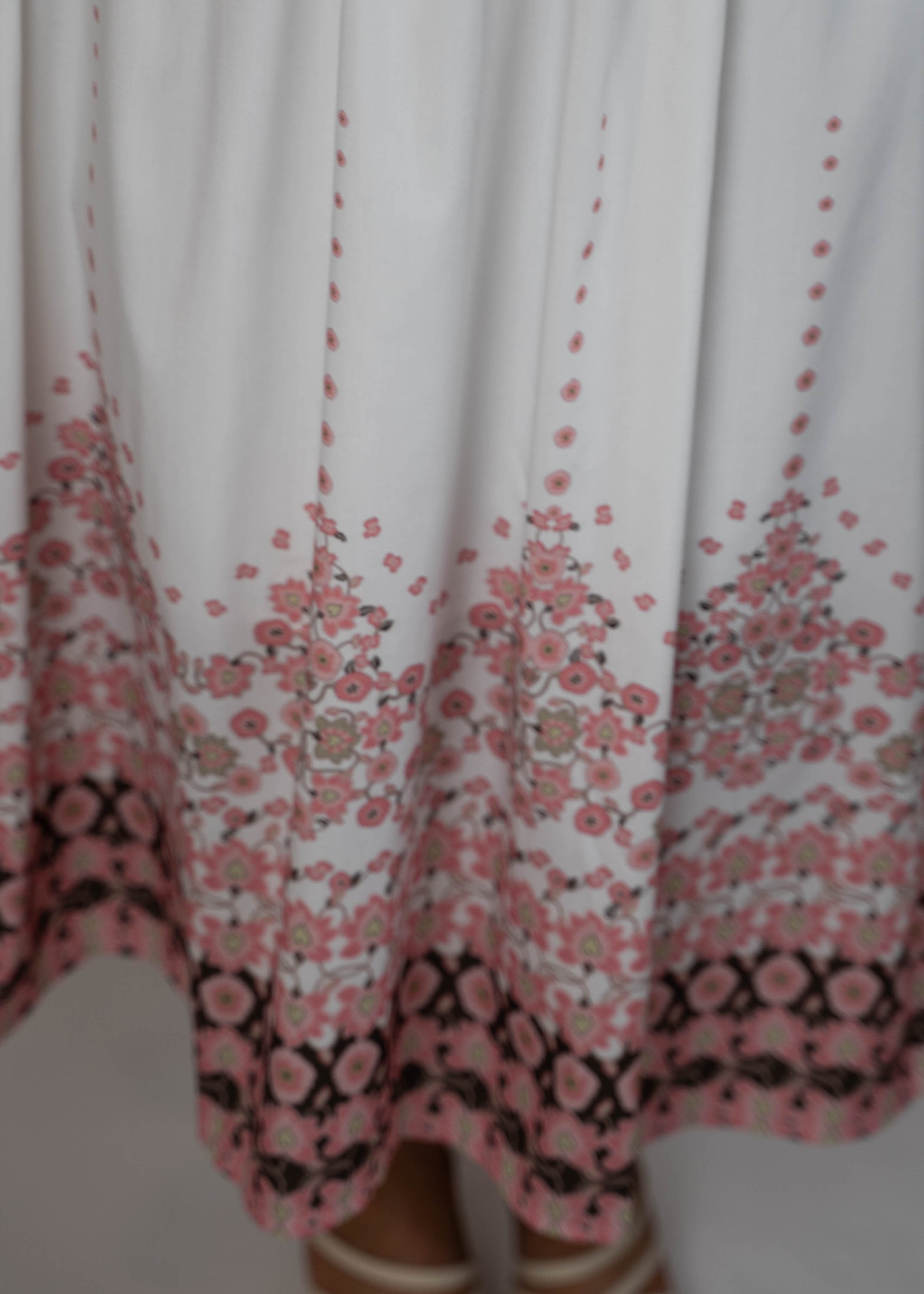 White maxi midi dress with pockets and pink flowers at the hem and ties on the shoulders. Elegant and feminine, perfect for a stylish summer look