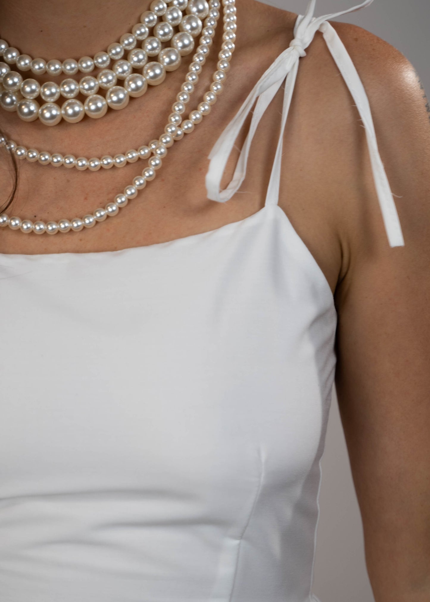 White maxi midi dress with pockets and pink flowers at the hem and ties on the shoulders. Elegant and feminine, perfect for a stylish summer look