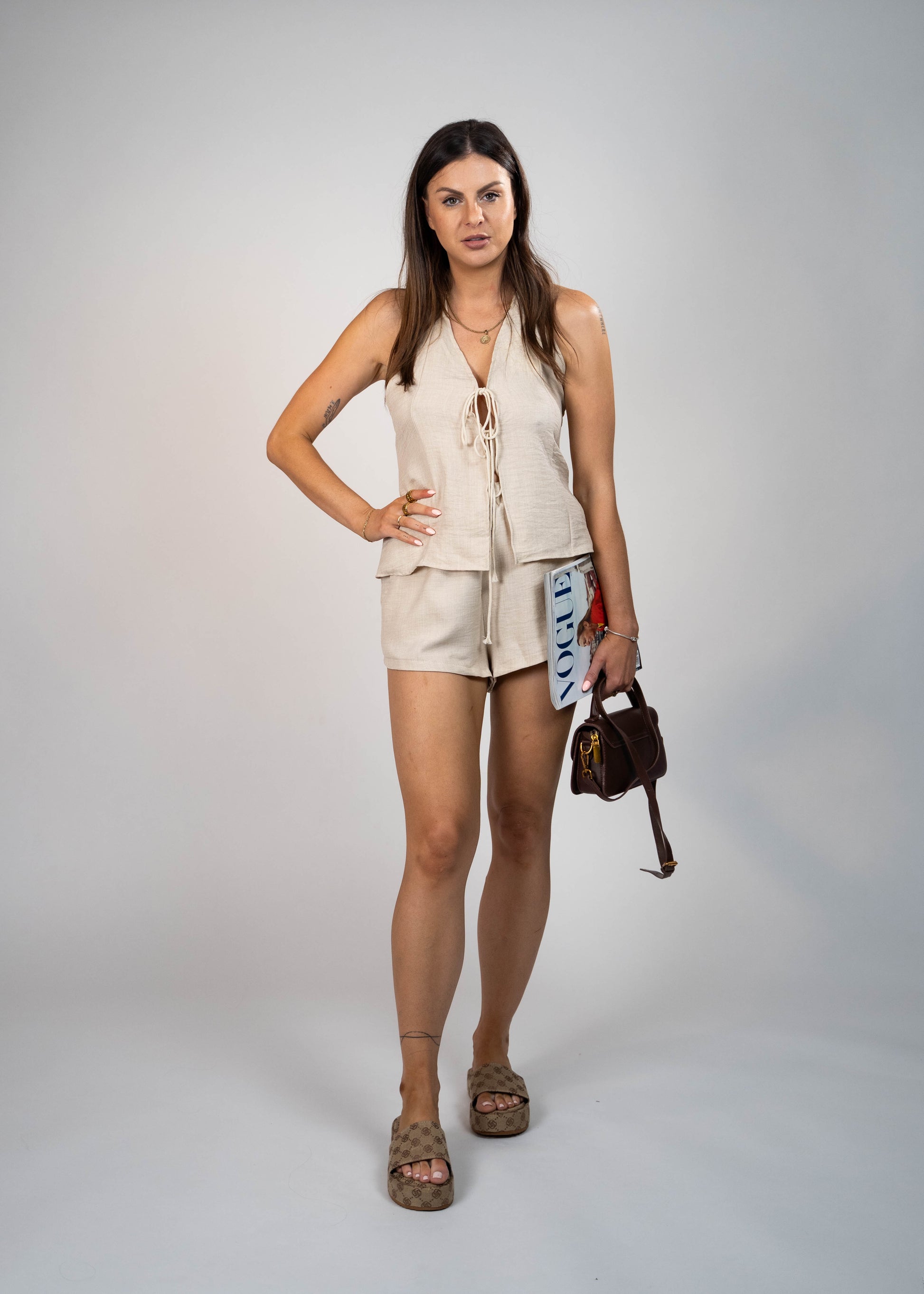 Beige summer set made of breathable linen, featuring shorts with pockets and a stylish front and back tie top. Perfect for staying cool and chic in warm weather."