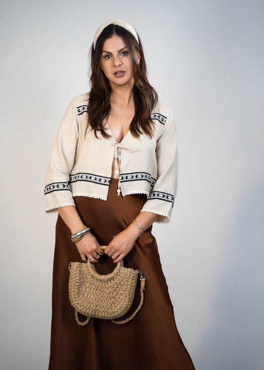 Trendy cream-colored front-tie top with 3/4 loose sleeves. Light and easy to style, featuring a chic front tie for added flair.